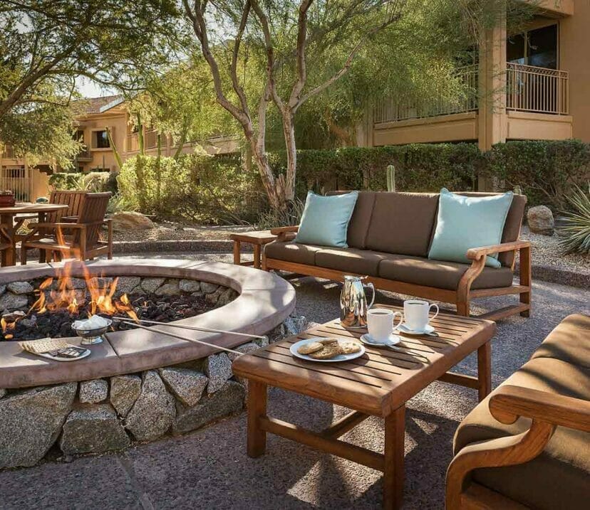 firepit surrounded by wooden tables chairs and couches
