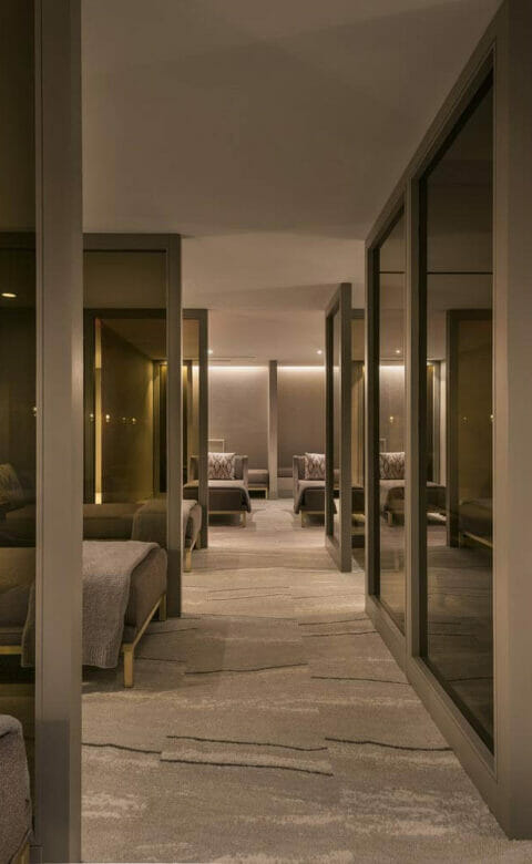 rows of daybeds, separated by glass panes, in a comfortable and dimly lit spa post-treatment room