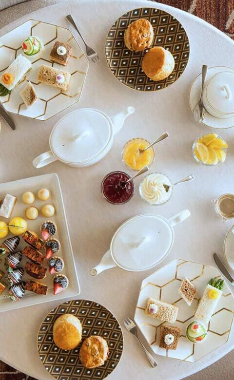 afternoon tea table prepared for dining guests with tea, biscuits, and a tray of sweets