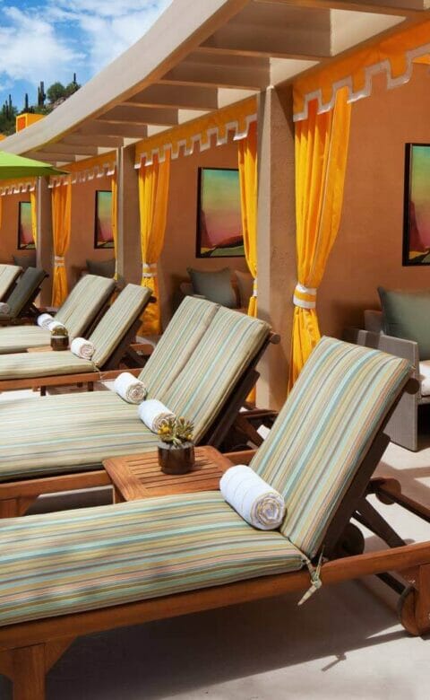 line of cabanas with yellow curtains long lounge chairs and umbrellas in front of them