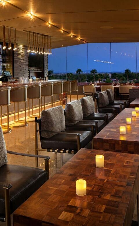 JG Steakhouse bar with high chairs lining the bar and floor-to-ceiling windows looking out on the resort