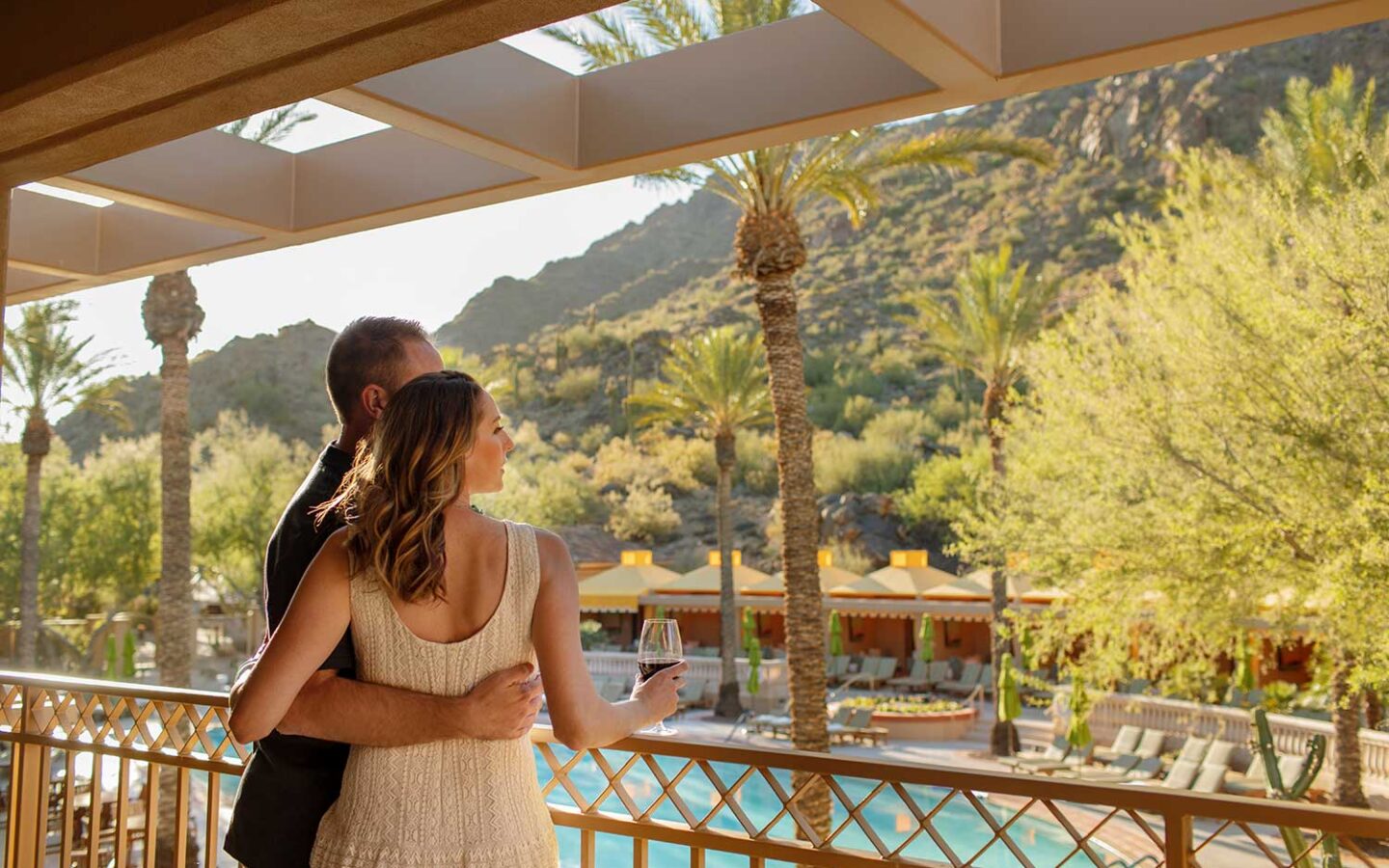 man and woman standing on balcony overlooking pool