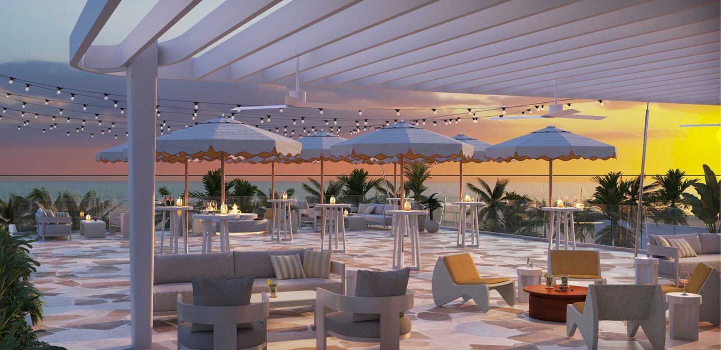 Mezzanine deck overlooking the ocean with shaded tables, lounge chairs, and string lights.